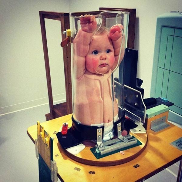 这个可爱的宝宝被卡在一个透明的容器中，原来这是给婴儿做x射线的仪器-1435754370