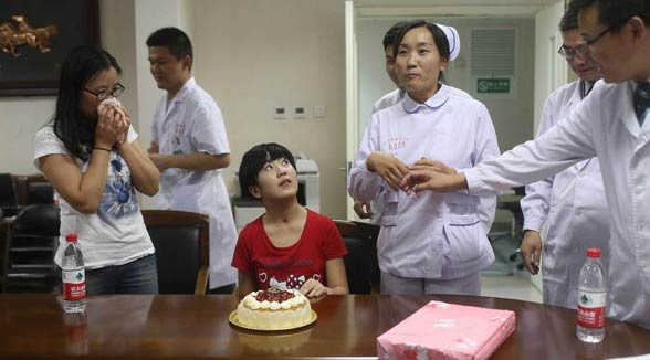 图为赵英男在妈妈和医护人员陪同下许愿，切蛋糕。